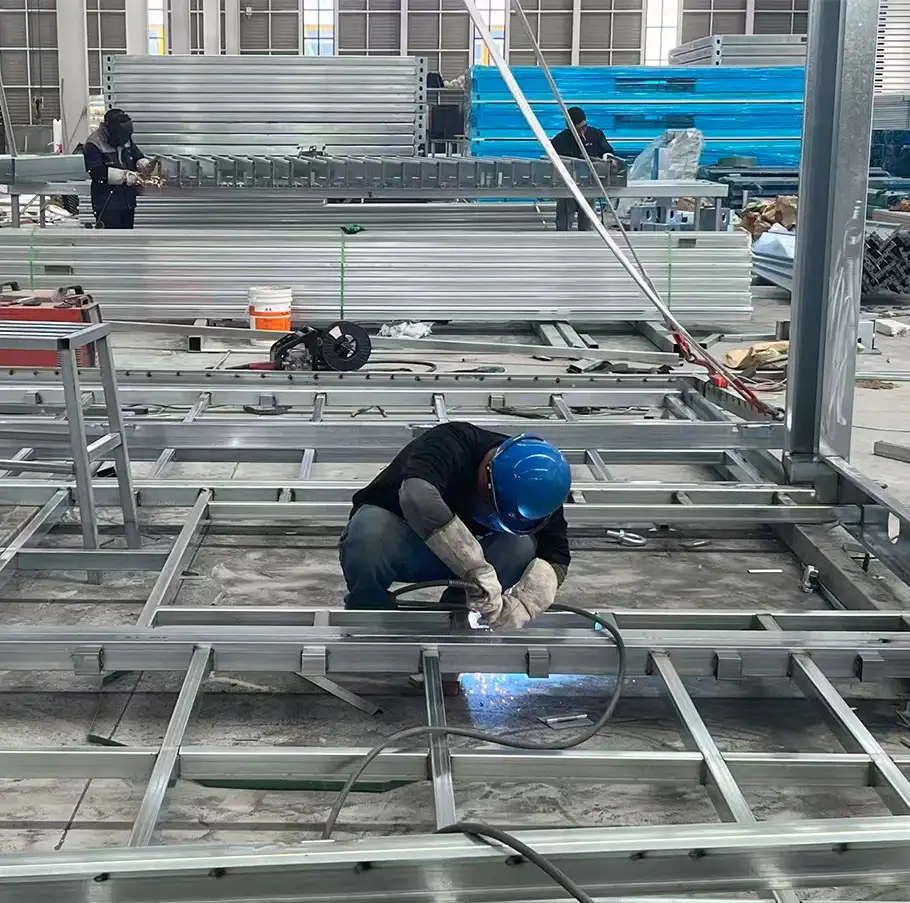 Worker welding steel frame for container house and capsule house production